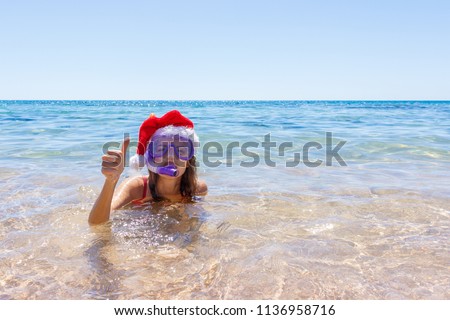 Beach vacation fun woman wearing a mask tube and christmas hat for swimming in ocean water. Close-up portrait of a girl in her travel holidays. copy space.