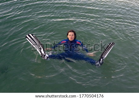 Beach vacation fun woman wearing a wetsuit and flippers making a face while swimming in ocean water