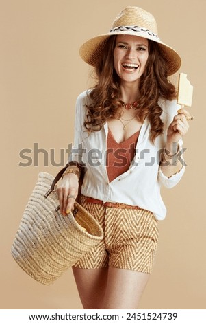 Beach vacation. happy stylish woman in white blouse and shorts on beige background with straw bag, ice cream and straw hat.