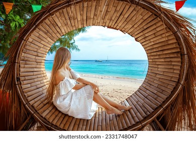 Beach vacation influencer poses on tropical paradise beach with blue sea in the background. Summer holiday and travel concept.