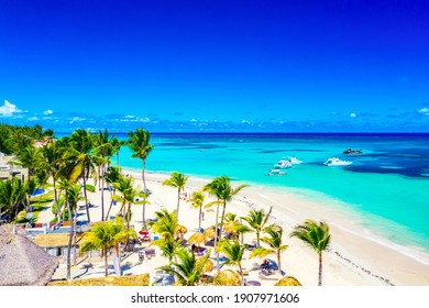 Vacaciones en la playa y antecedentes de viaje. Vista aérea por drones de una hermosa playa atlántica tropical con sombrillas de paja, palmeras y barcos. Playa Bávaro, Punta Cana, República Dominicana.