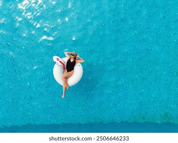 Beach vacation woman relaxing in pool float unicorn inflatable ring floating on turquoise pool water. Aerial top view from drone - Powered by Shutterstock