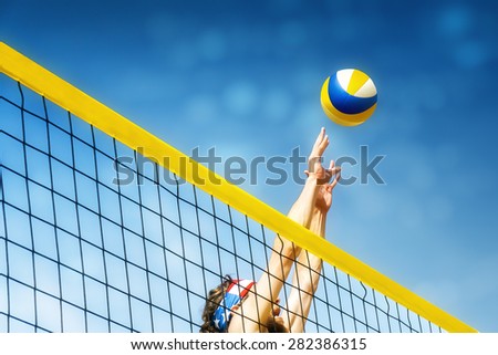 Beach volley ball player jumps on the net and tries to  blocks the ball