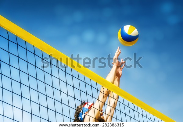 Beach volley ball player jumps on the net and tries\
to  blocks the ball