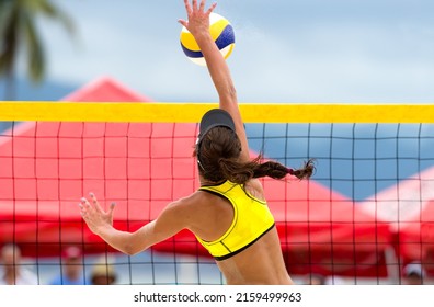 A Beach Volleyball Player Is Jumping At the Net And Spiking The Ball - Powered by Shutterstock