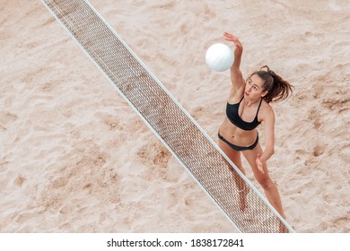 Beach volleyball player jumping to spike volleyball over net. Summer vacation and sport concept. Vintage color filter