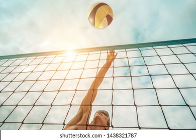 Beach Volleyball player in sunglasses in action with ball under sunlight. Popular Dynamic outdoor sport for people.