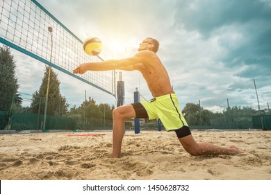 Beach Volleyball player in sunglasses in action with ball under sunlight. Popular Dynamic outdoor sport for people.