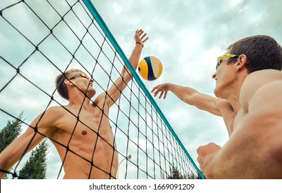 Beach Volleyball players in sunglasses in action with ball under sunlight. Popular Dynamic outdoor sport for people.