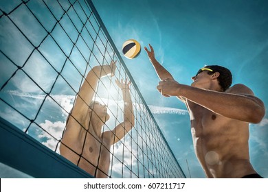 Beach Volleyball players in sunglasses under sunlight. Dynamic sport action near the net, outdoor.