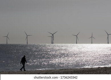 Beach Walk. Morning Coronavirus Covid19 Lockdown Isolation Exercise By Alternative Energy Offshore Wind Farm Turbines. Person Walking Alone Along The UK Coast At Dawn. Healthy Lifestyle.