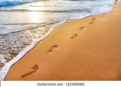 beach, wave and footprints at sunset time - Powered by Shutterstock