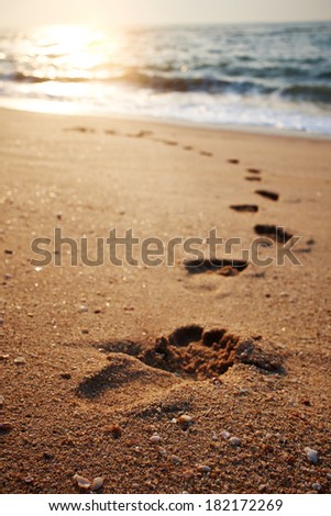 beach, wave and footsteps at sunset time 