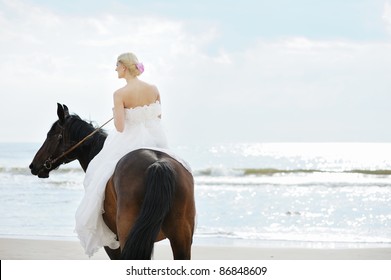 Beach wedding: bride on a horse by the sea