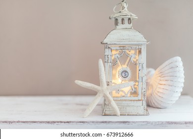 Beach Wedding Interior Decor. Natural Seashell And Lantern On Vintage Shelf Over Pastel Wall.