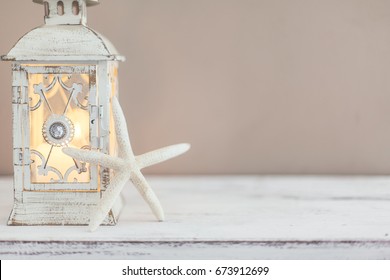 Beach Wedding Interior Decor. Natural Seashell And Lantern On Vintage Shelf Over Pastel Wall.