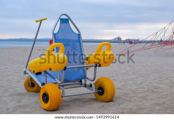 Beach wheel chair for disabled swimmers in the\
beach on blue sky and sea background. Concept of access to sea\
bathing and swimming for the disabled and people with reduced\
mobility. Summer\
vacation.