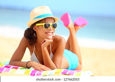 Beach woman funky happy and colorful wearing sunglasses and beach hat having summer fun during travel holidays vacation. Young multiracial trendy cool hipster woman in bikini lying in the sand. - Powered by Shutterstock