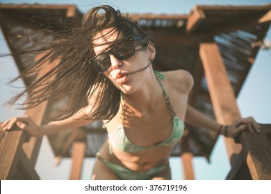 Beach woman having fun in summer vacation holidays.Lifestyle summer portrait,relaxed standing on the lifeguard tower.Happy woman dancing on the beach.DJ on the beach party