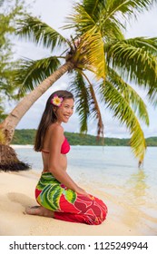 Beach Woman Relaxing On Bora Bora Tahiti Island Under The Sun Wearing Polynesian Skirt And Monoi Flower With Palm Tree Background. Polynesia Culture Travel Concept.