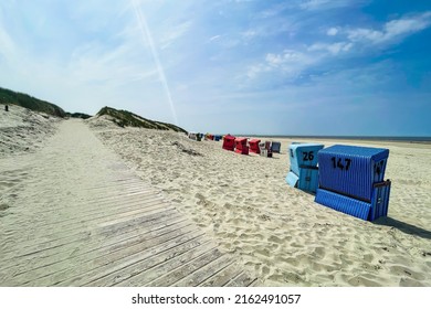 Beach With Wooden Plank Walkway And Strandkorb Beach Chairs. Wide Shot. 