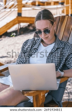 Beach workation digital nomad plans tasks with laptop and notebook on lounge chairs, powered by a portable solar charger. Eco-friendly, productive, flexible lifestyle by the sea. now