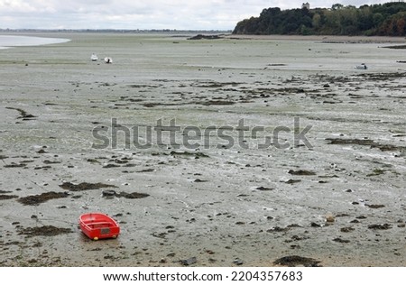 beached red Boat on the muddy sand at low tide in Europe