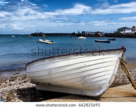 Beached rowing dinghy; white dinghy drawn up onto foreshore, against a beautiful ocean background
