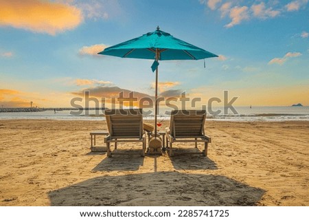 Beaches and sun tables in Thailand,Row of empty sun loungers and orange parasols on the tropical beach at sunset. Vacation in the all inclusive hotel on the Caribbean sea 