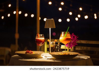 beachside dinner table,Beachside dinner table with one large challah, two bottles of red wine, two wine glasses, two tea lights in jars, one small vase with flowers, at night, with hanging light nearb - Powered by Shutterstock