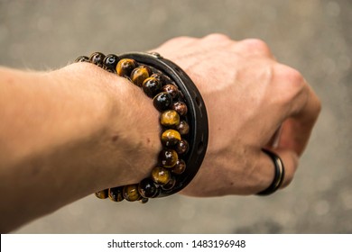 Beaded bracelets and leather bracelet on a wrist with a tungsten ring on the thumb