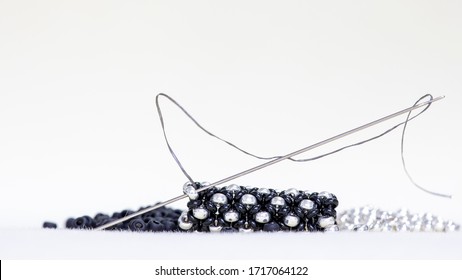 Beading beads black and silver with needle and threads.