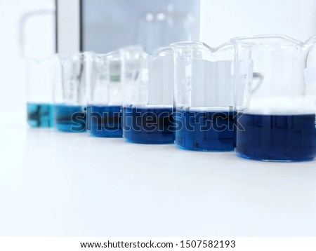 The beakers with blue color range  solution on bench laboratory, with stannous chloride solvent for analysis phosphate experiment in waste water sample. bright light effect using for clean room.