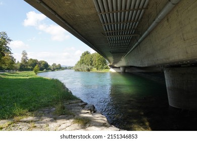 Beam bridge over river Limmat in canton Zurich, Switzerland. Low angle view showing cement pillars planted in the water. There are pipes attached to the bridge and crossing the river as well. 