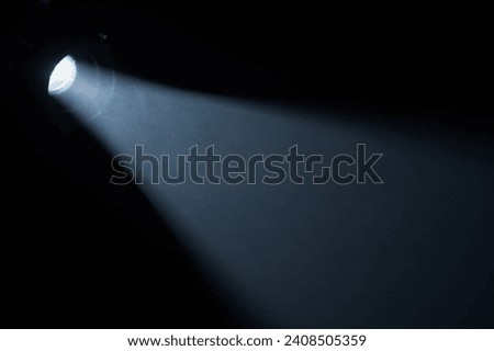 Beams of light from spotlight in dark studio with smoke. Stream of light from movie spotlight on black background. Particles of smoke floating in the rays of light.