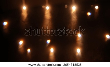 Beams of light from spotlight in dark studio with smoke. Stream of light from movie spotlight on black background. Particles of smoke floating in the rays of light.