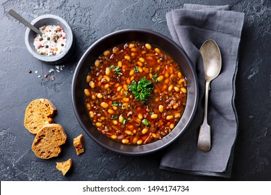 Bean Soup In A Black Bowl. Dark Background. Top View.