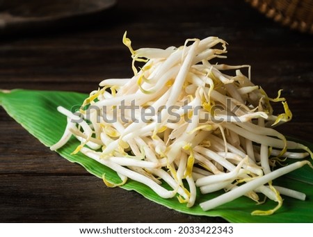 bean sprouts piled on green leaves on old wooden board