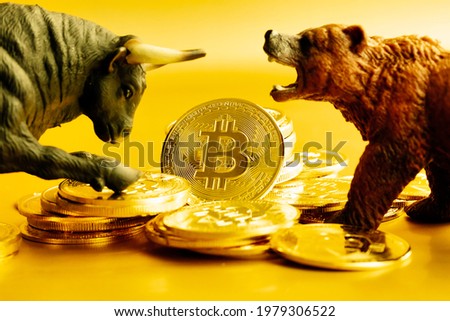 Bear and bull fighting over bitcoins against golden background. Market trend concept. 