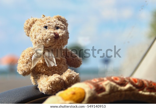 Bear put on\
the car console with blur\
background