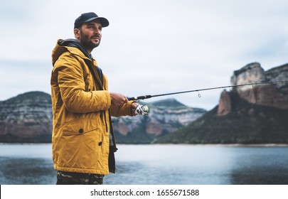 beard fisherman hold in hand fishing rod, man enjoy hobby sport on mountain river, person catch fish on background nature blue sky, fishery concept - Powered by Shutterstock