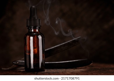 Beard Grooming Concept, Bottle With Dropper Old Shaving Razor In Close-up On Dark Wooden Background Barber Shop Tools On Wooden Background Plus Smoke. MOCKUP For Product.