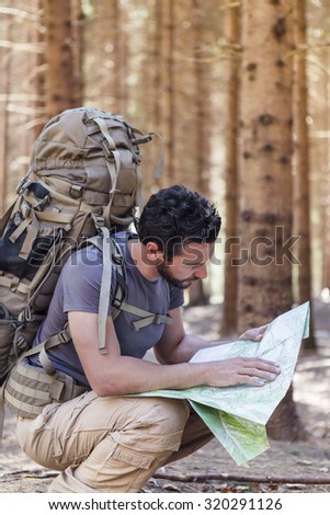 Beard Man with Backpack and map searching directions in wilderness area
