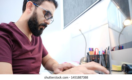 Beard Man Working At Home In Desktop And Cellphone. The Man Is Serious Mood And Concentrate In Office Enviroment.