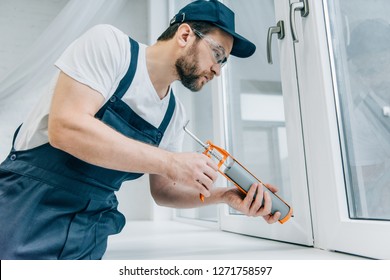 Bearded Adult Repairman Fixing Window With Sealant Gun