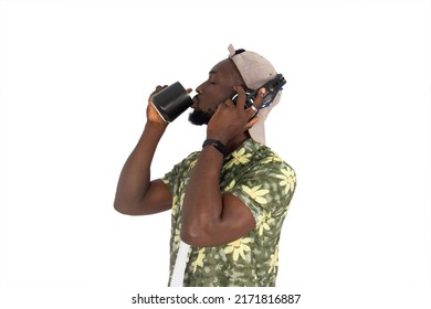 Bearded African Man Wearing A Hat With A Cup In His Hands Drinking Coffee, And Looking In Profile Listening To The Music. Addicted To Coffee Or Tea. Coffee Flavor