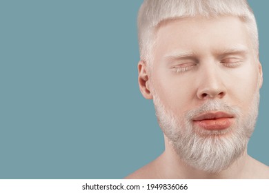 Bearded albino man posing with closed eyes against turquoise background, empty space. Guy with unusual appearance, white hair, eyelashes and brows. Albinism, abnormal deviations concept