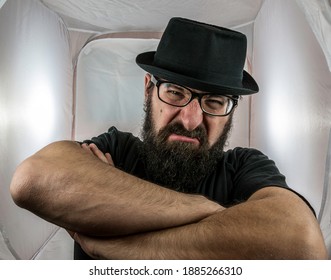 A Bearded And Angry Looking Man, Looking Like A Doorkeeper With Black Glasses And Hat