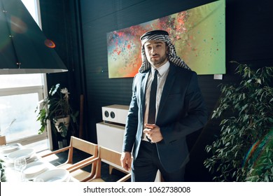 Bearded Arab Businessman In Suit Standing Near Dinner Table At Hotel Room.