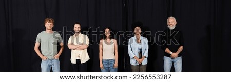 bearded art director with young interracial actors smiling at camera in theater school, banner